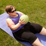 woman doing exercises on mat on lawn