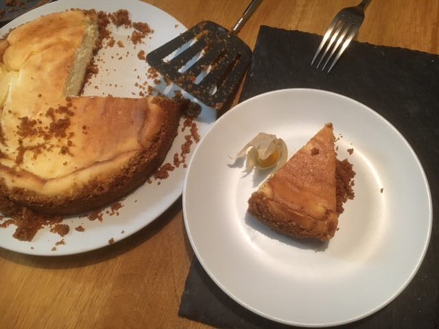 large lemon cheesecake with slice on separate small plate, crumbly