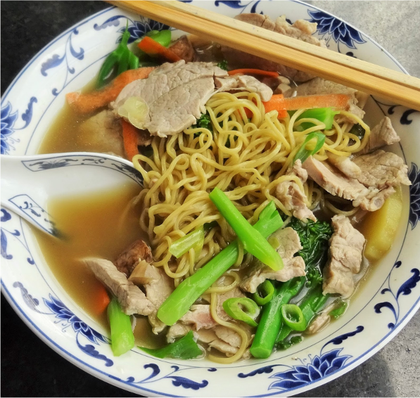 CC noodle dish on plate with meat slices, green beans, chop sticks