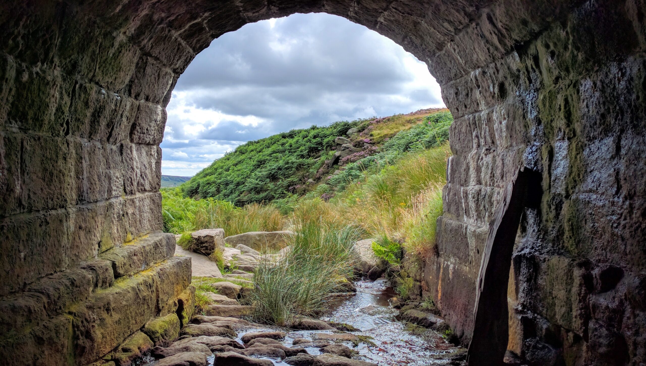 view onto fields and blue sky from arch under bridge, Hathersage